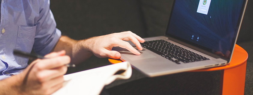 Person using a laptop while writing